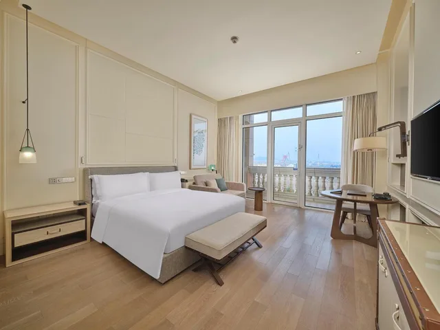 غرفة ديلوكس بسرير كينج بإطلالة على البحر بشرفة مع أريكة، Hilton Dalian Golden Pebble Beach Resort 2/6