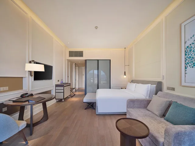 غرفة ديلوكس بسرير كينج بإطلالة على البحر بشرفة مع أريكة، Hilton Dalian Golden Pebble Beach Resort 5/6