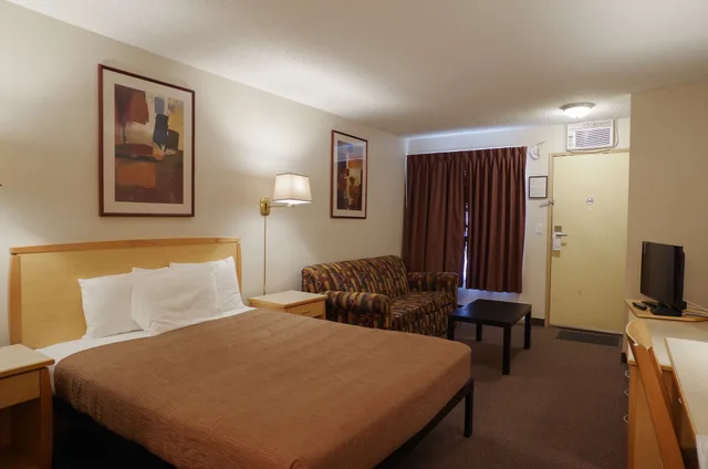 غرفة بسرير كوين مع أريكة بمطبخ صغير، EasyStay Inn & Suites Fernie 1/3