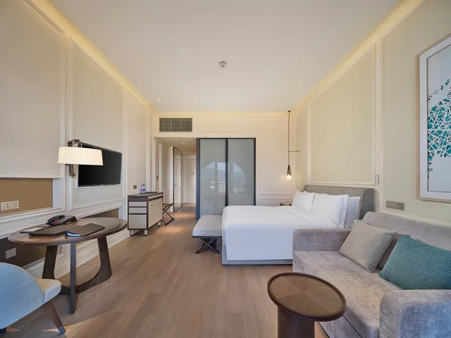 غرفة بسرير كينج بإطلالة على البحر بشرفة مع أريكة، Hilton Dalian Golden Pebble Beach Resort 5/5